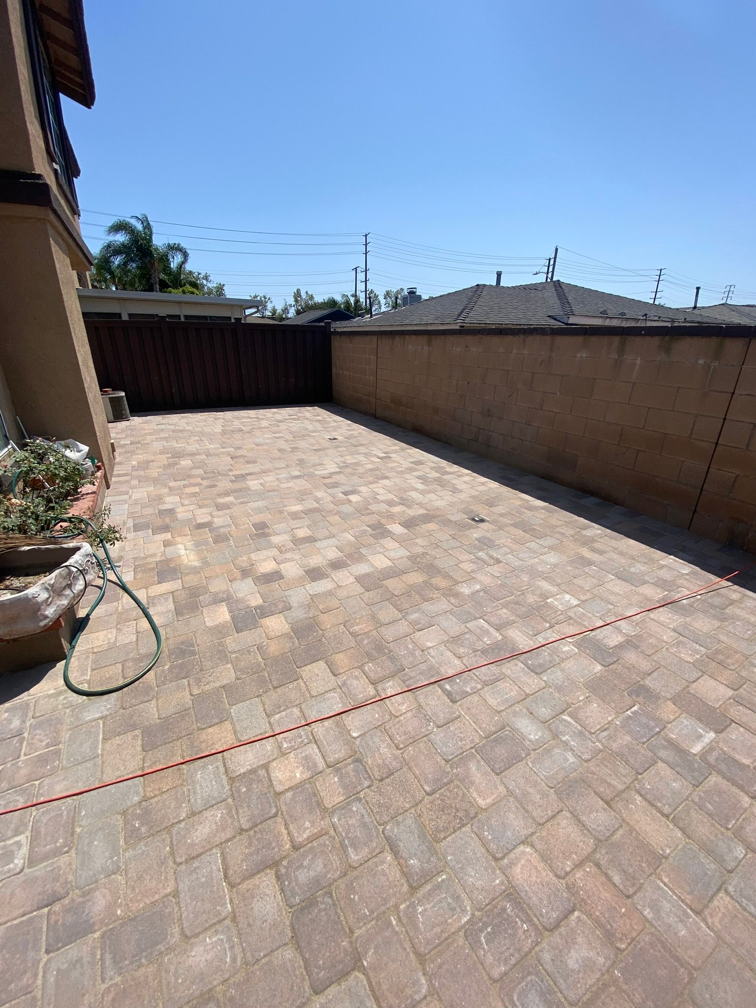 Brick patio enclosed by brown walls and fence under a blue sky.