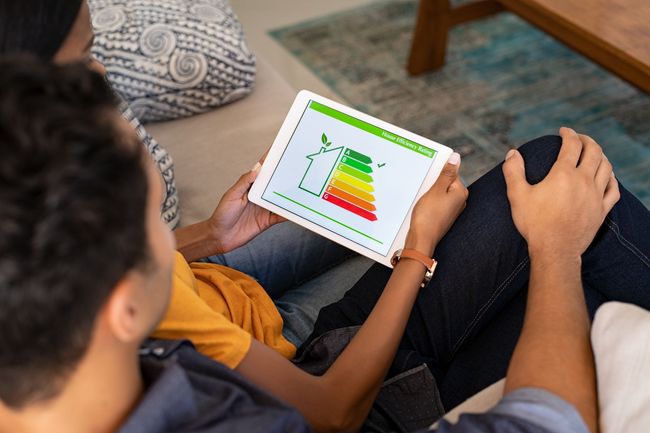 A man and a woman are sitting on a couch looking at a tablet.