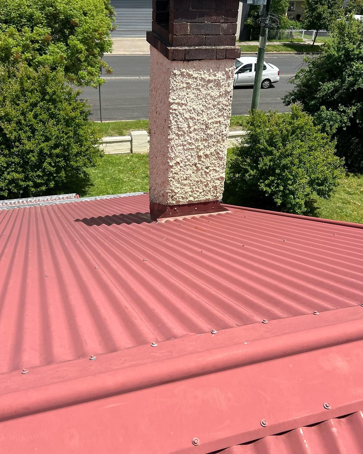Red Corrugated Metal Roof With Brick and Stucco Chimney — Ace Metal Roofing in Maclean, NSW