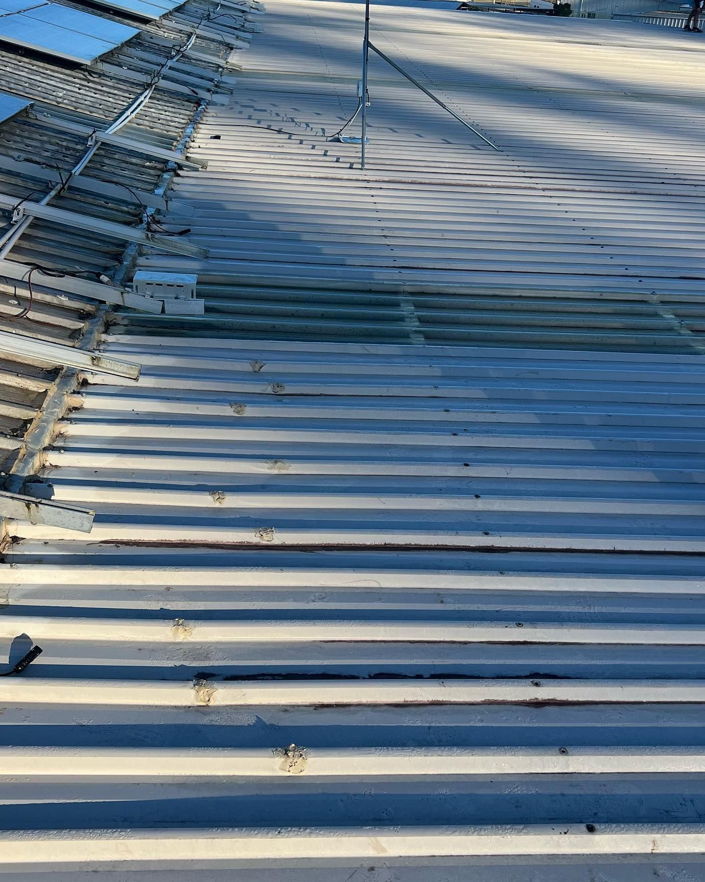 A Corrugated Metal Roof, With Missing Sections and a Ladder Frame, in Sunlight — Ace Metal Roofing in Yamba, NSW