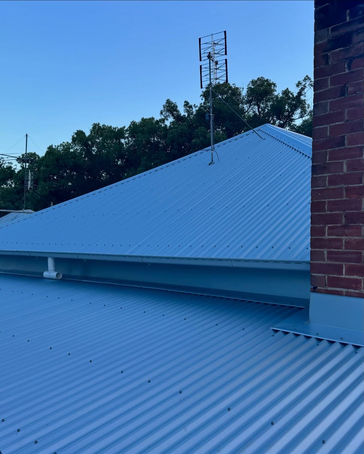 Blue Corrugated Metal Roof With Tv Antenna, Against a Clear Blue Sky — Ace Metal Roofing in Waterview Heights, NSW