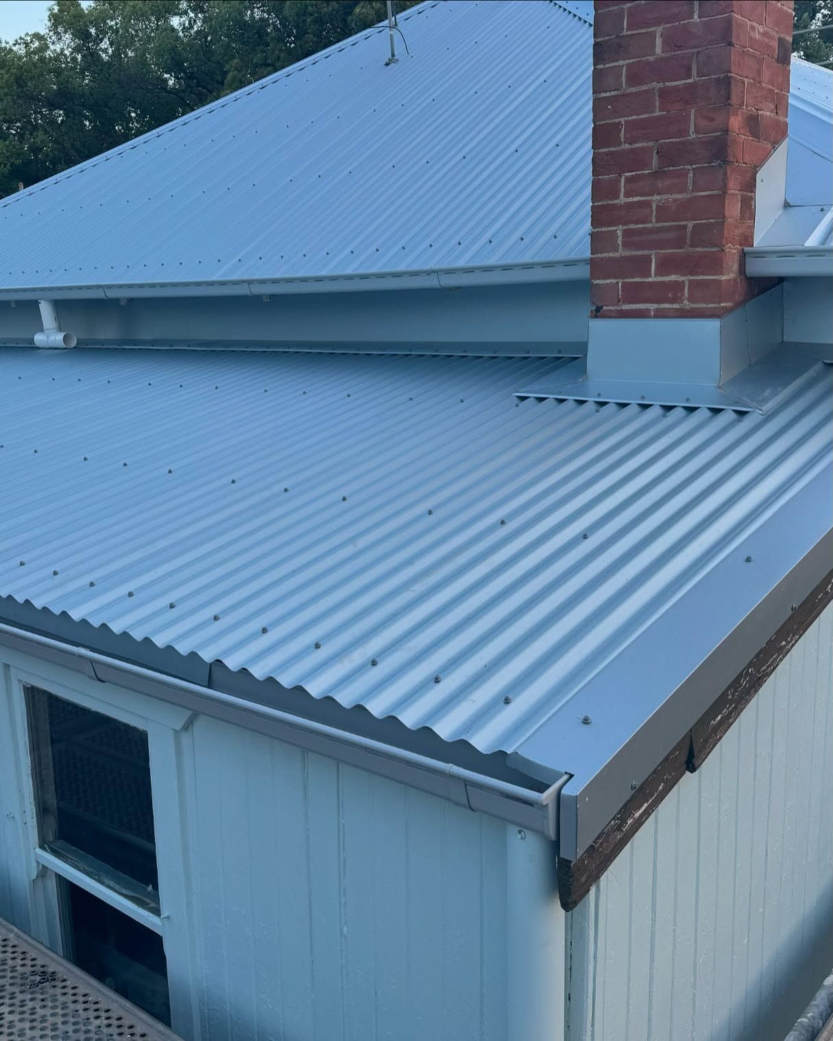 Gray Corrugated Metal Roof on a Light Blue House With a Brick Chimney — Ace Metal Roofing in Waterview Heights, NSW