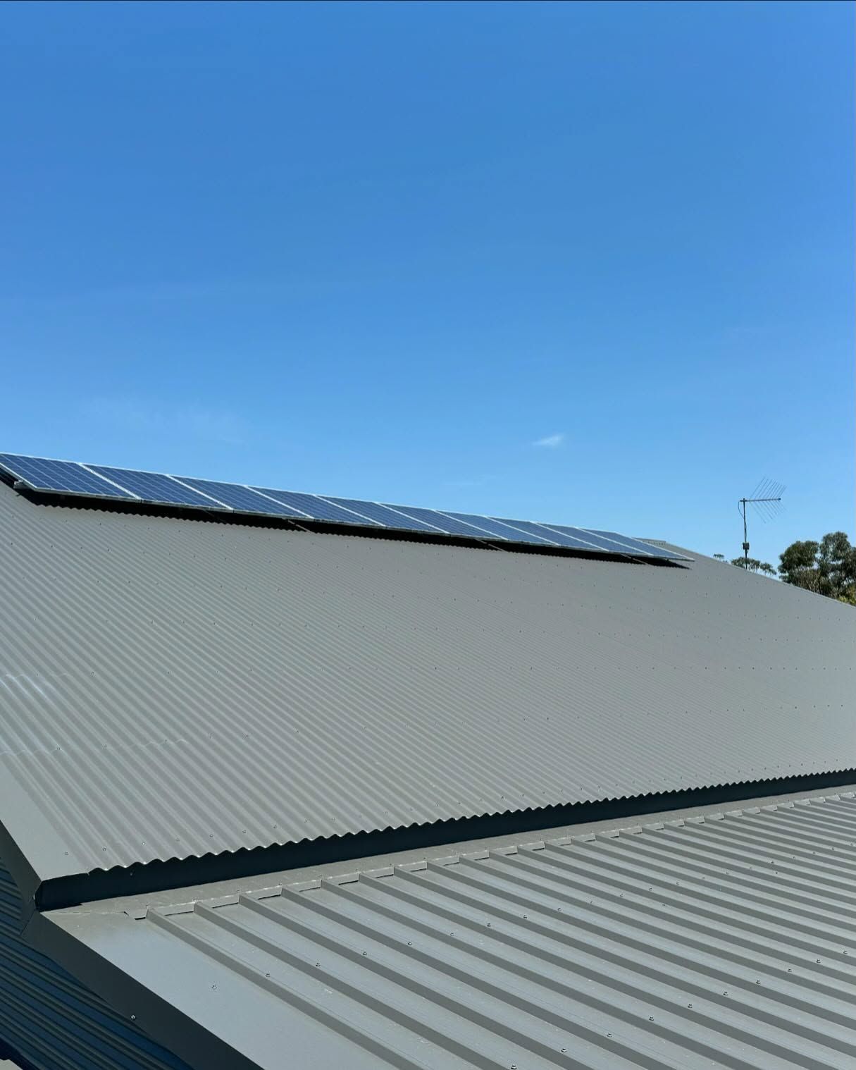 Solar Panels on a Gray Corrugated Metal Roof Against a Bright Blue Sky — Ace Metal Roofing in Waterview Heights, NSW