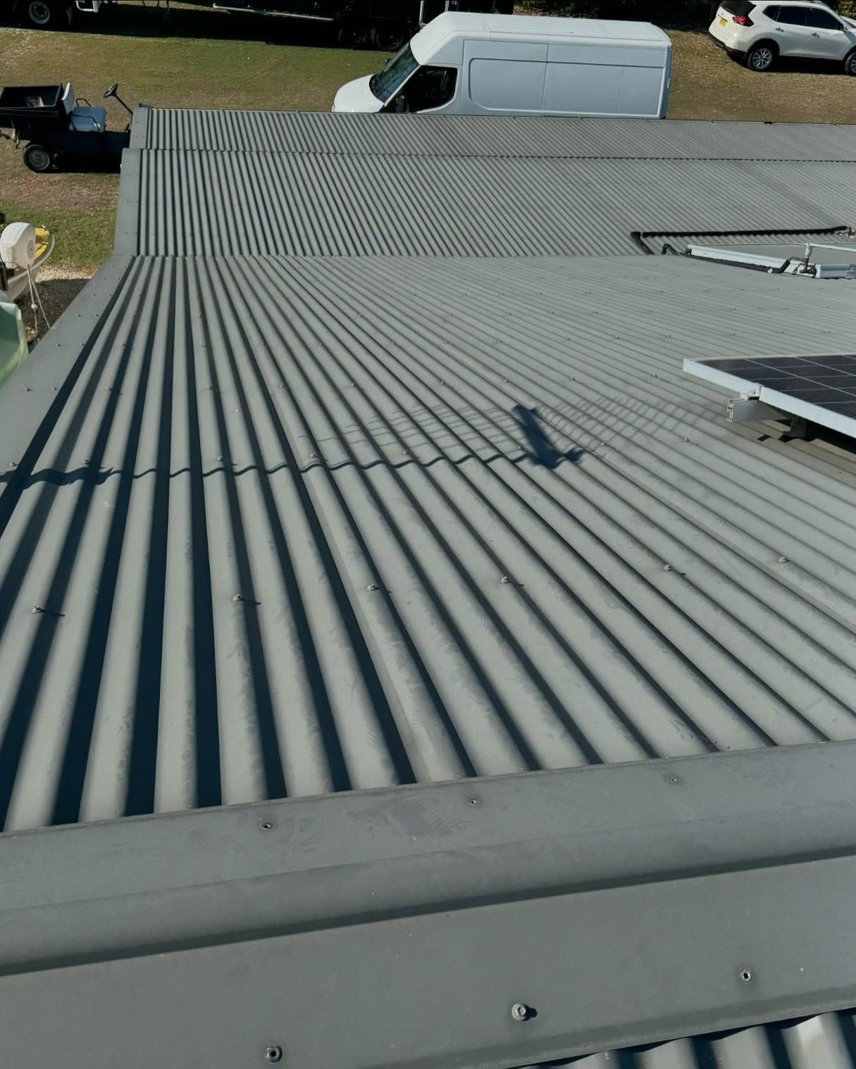A Corrugated Metal Roof With Shadows Cast Across It — Ace Metal Roofing in Waterview Heights, NSW