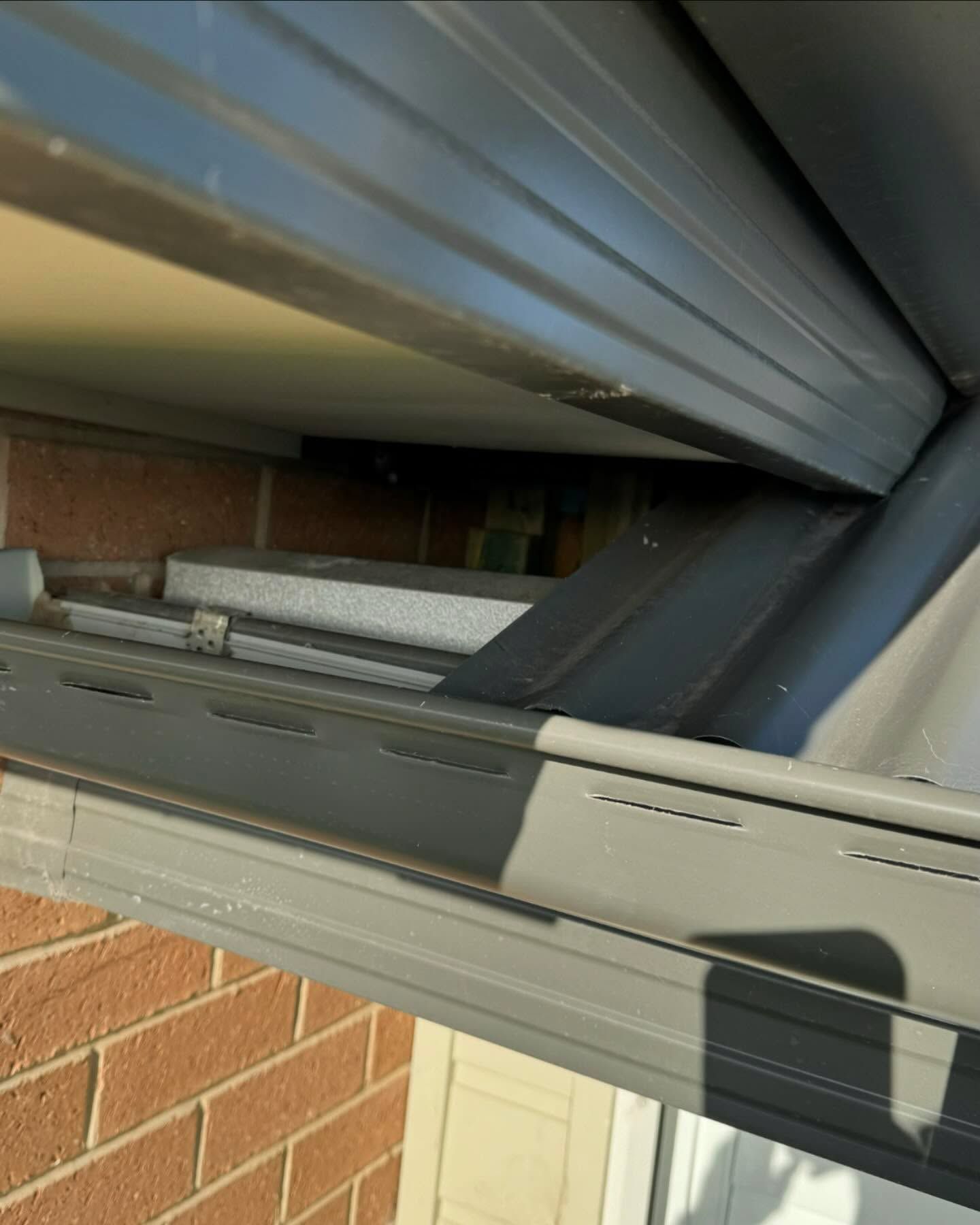 Close-up of a House Gutter and Siding. Gray Metal Gutter Against a Brick Wall — Ace Metal Roofing in Waterview Heights, NSW