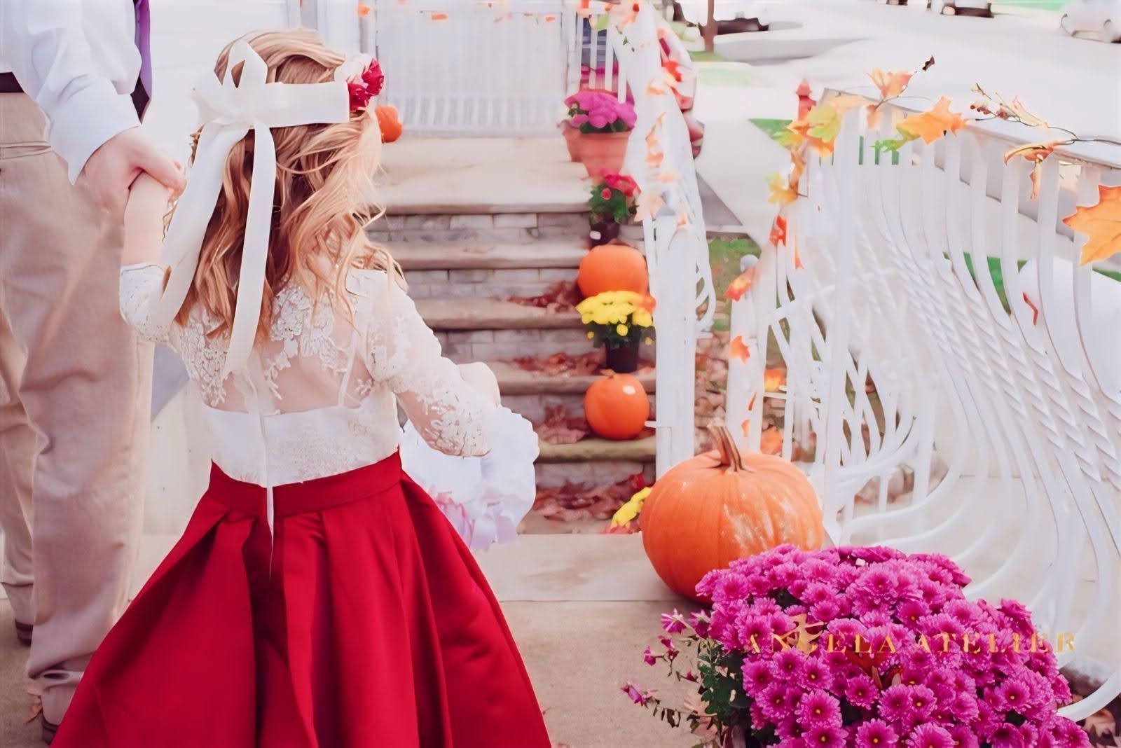 A little flower girl in a red dress is walking down a set of stairs.