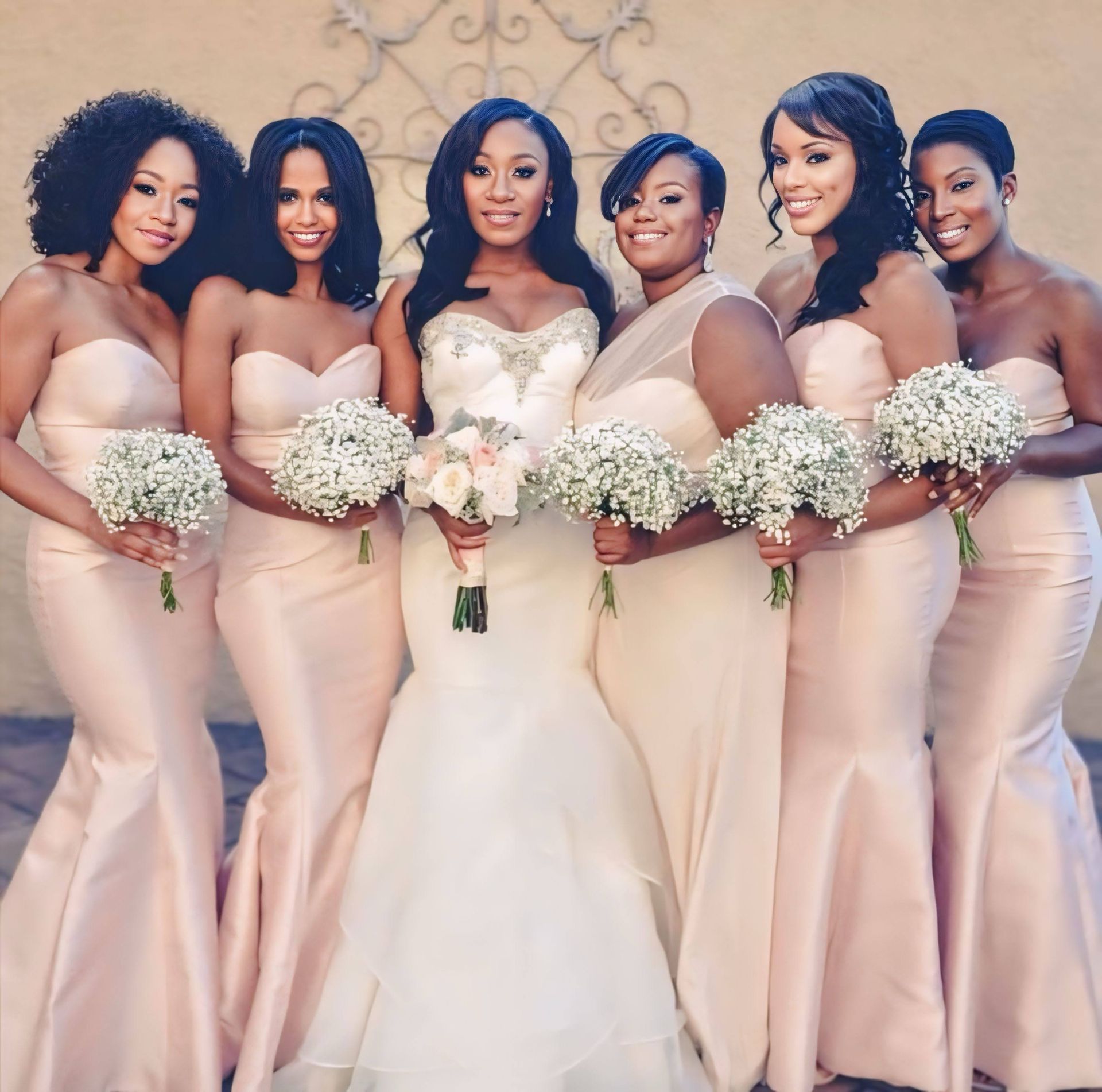 A bride and her bridesmaids are posing for a picture. fresh florals. bridal bouquet. bridesmaids bouquets. baby breath
