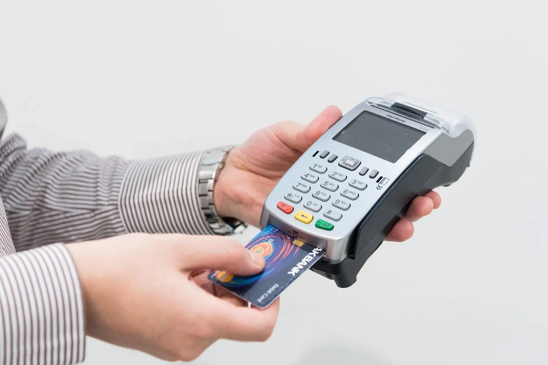 Person inserting a credit card into a POS (point-of-sale) terminal for payment processing.