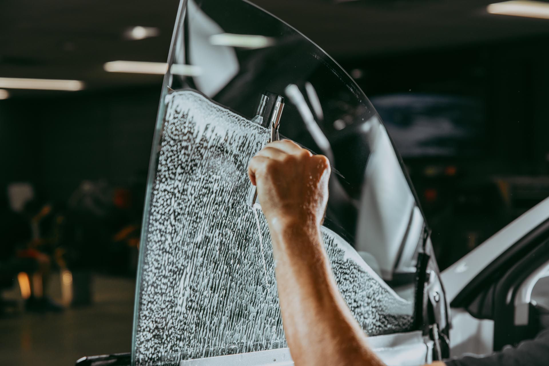 A person is applying tinted glass to a car window.