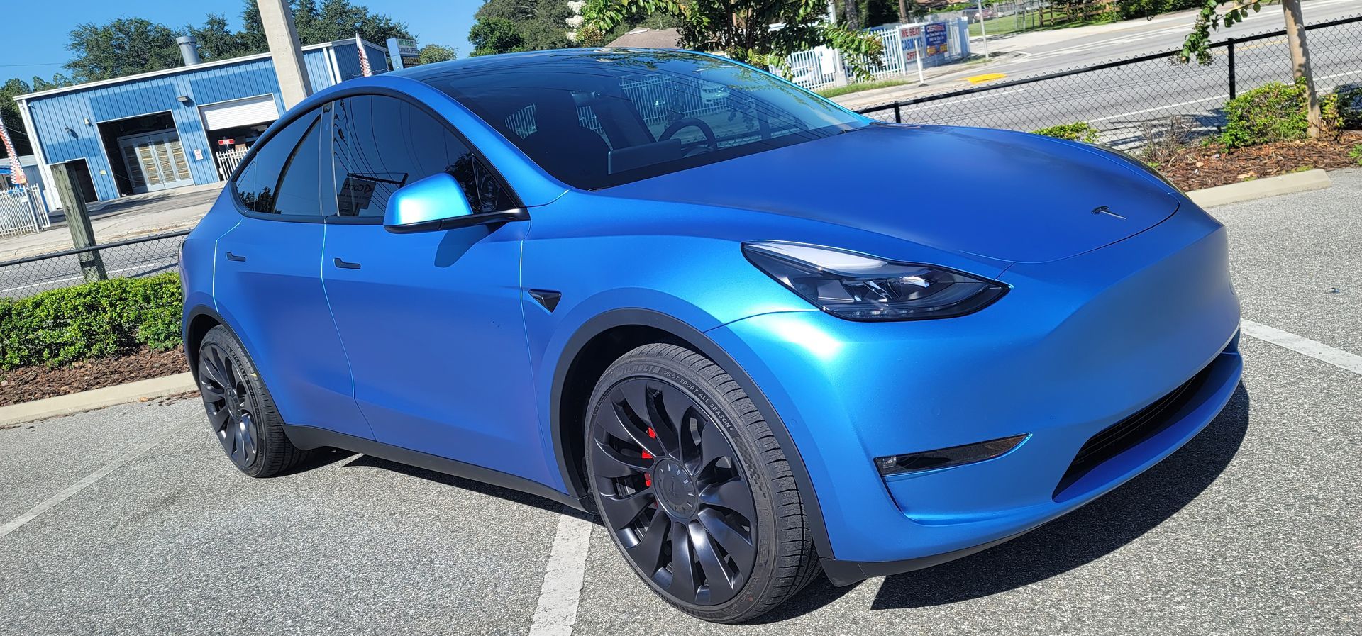 A white tesla model y is sitting on a lift in a garage.