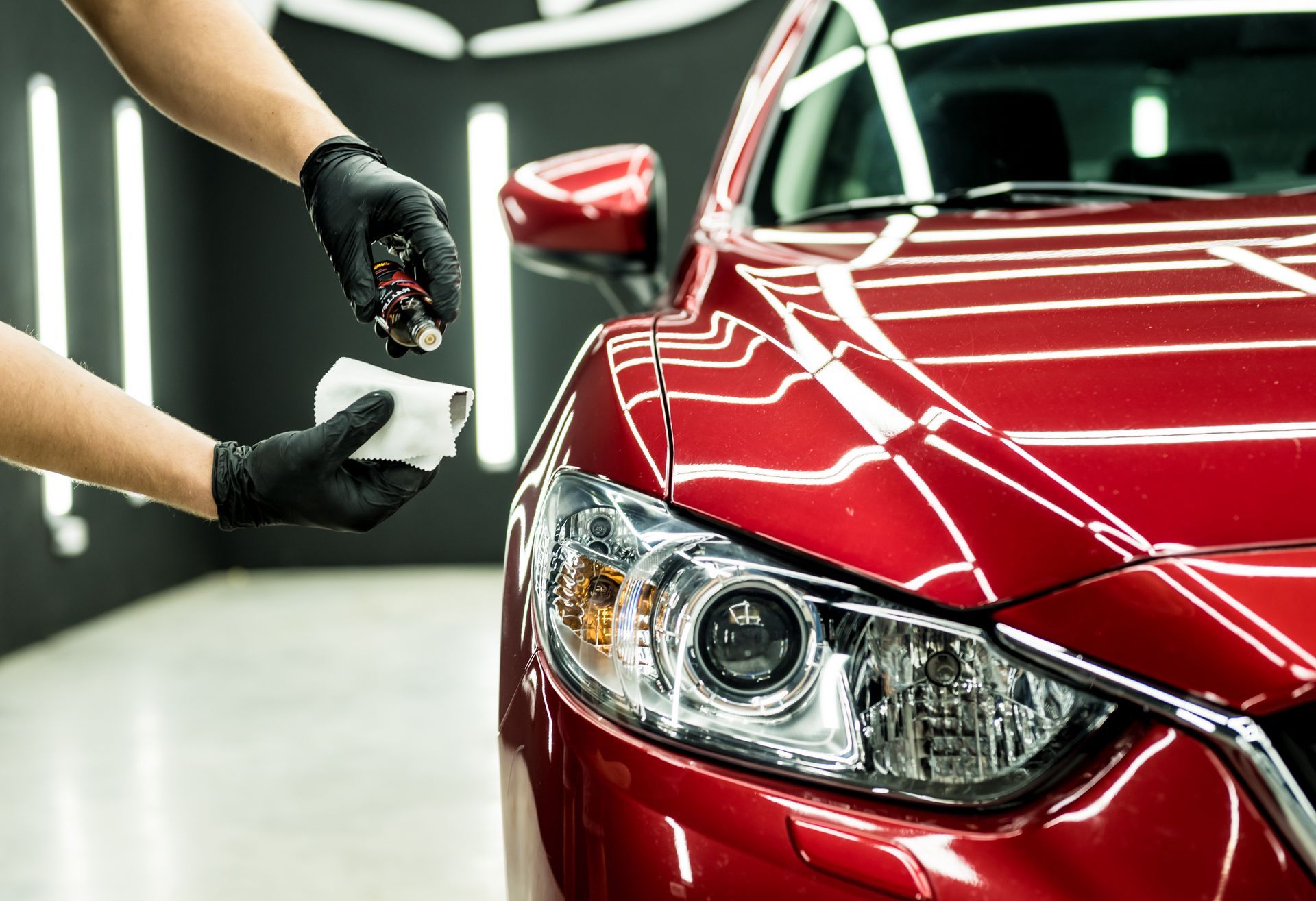 A person is polishing a red car in a garage.