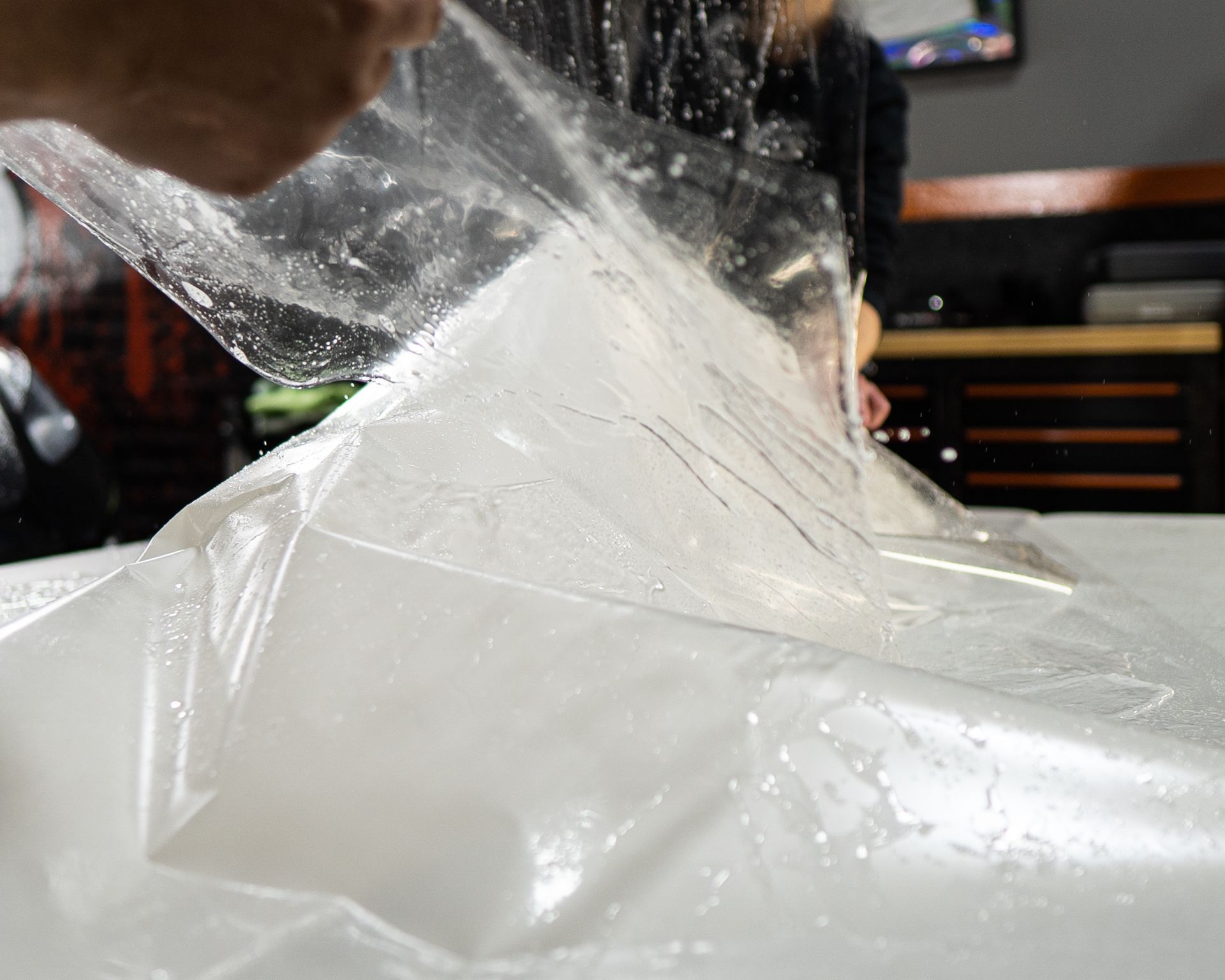 A person is holding a piece of plastic over a white surface.