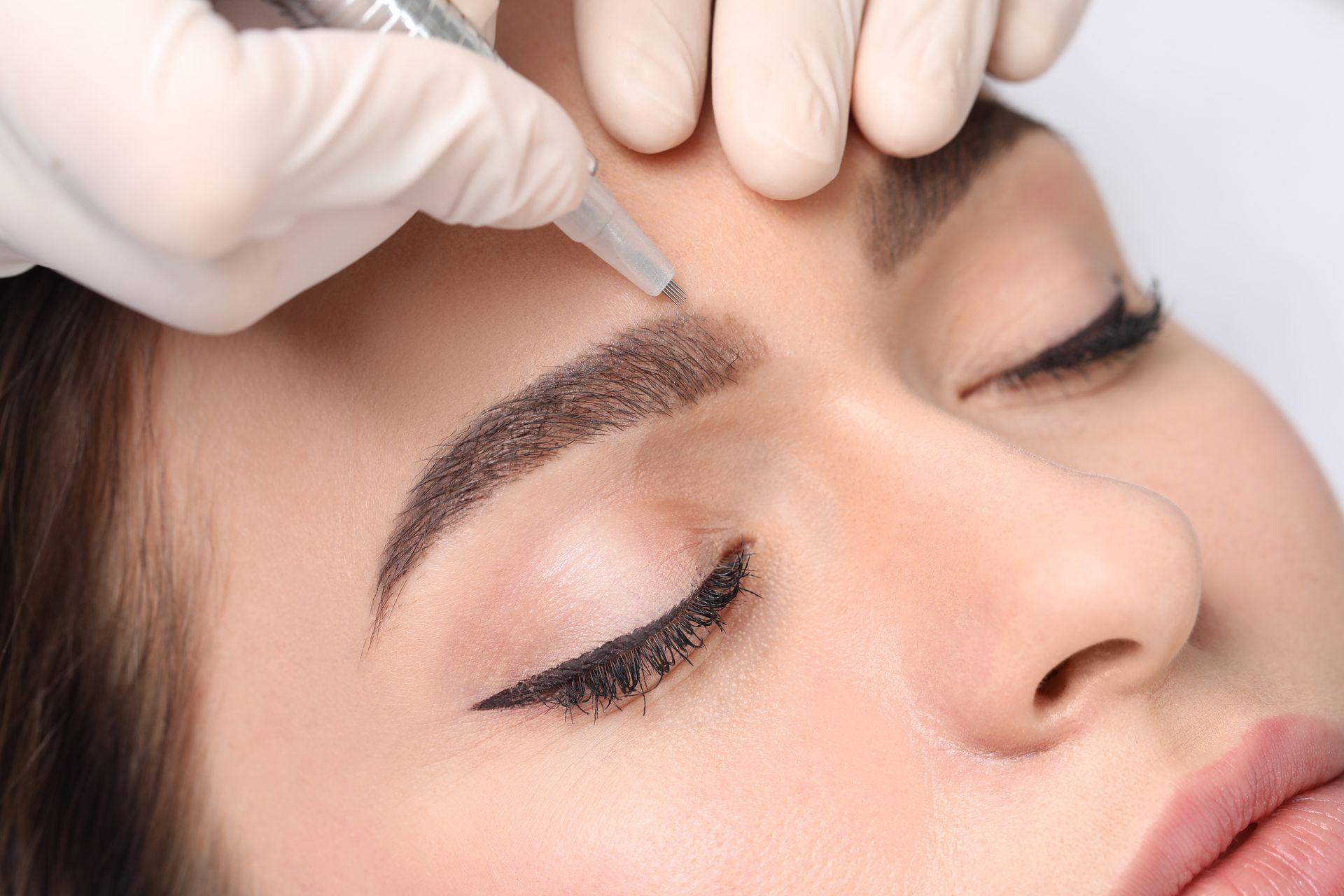 A woman is getting permanent makeup on her eyebrows.