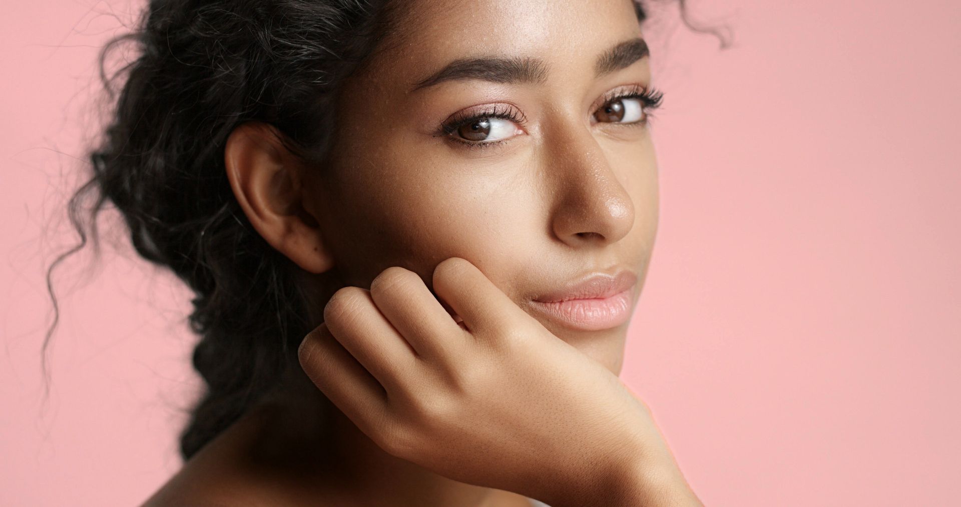 A close up of a woman 's face with her hand on her chin.