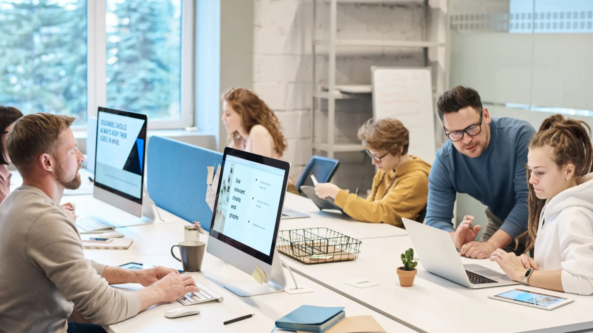 Diverse colleagues collaborate at their workstations in a bright, modern open-plan office.