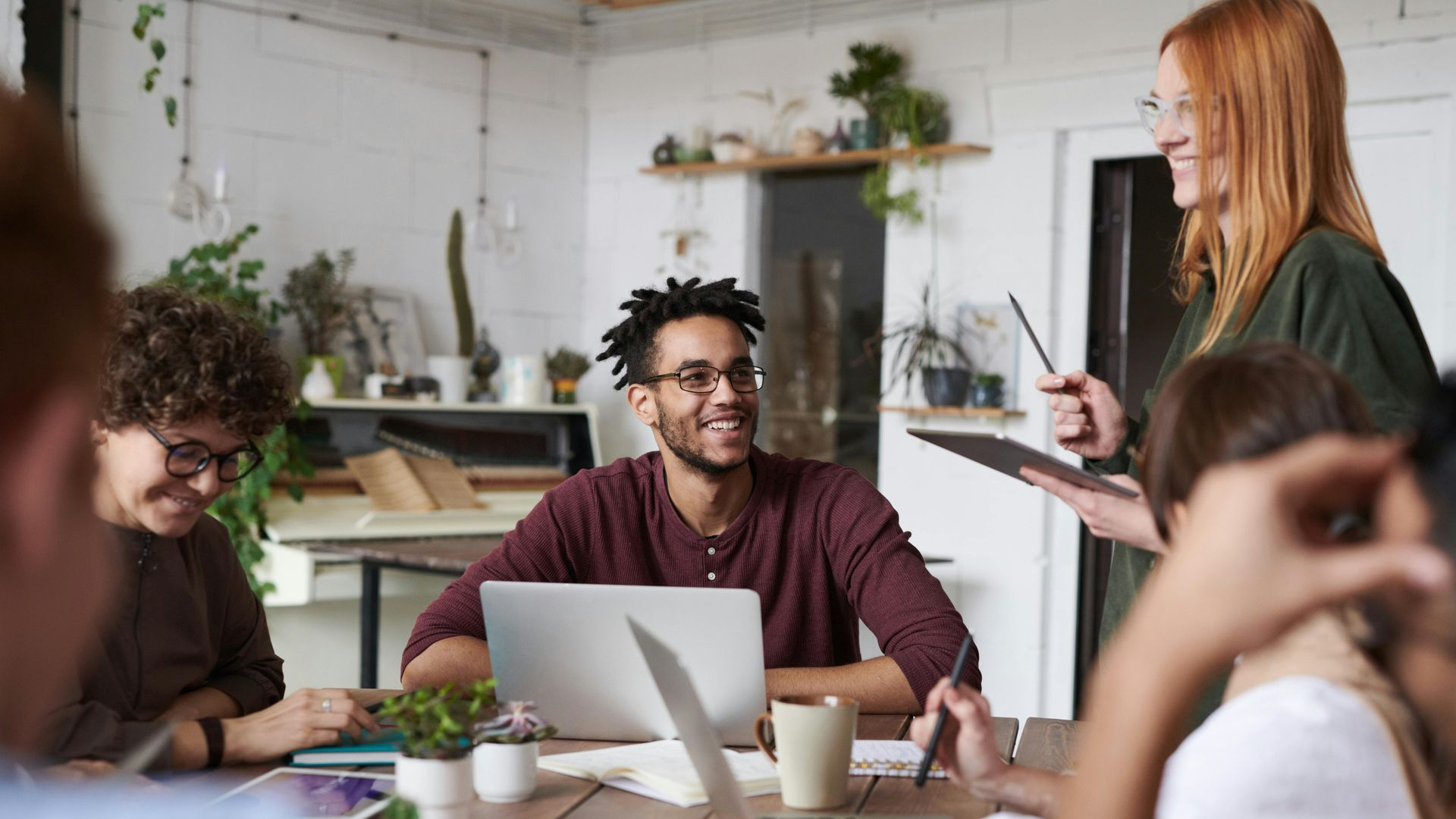 A group of people working together in a bright, modern office, engaged in a collaborative discussion around a table.