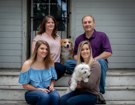 Family and two dogs pose on porch steps Family and two dogs pose on porch steps