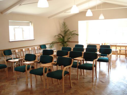 A room with rows of green chairs and tables