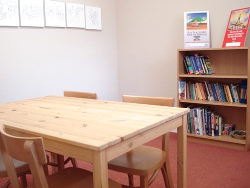 A room with a table and chairs and a bookshelf full of books