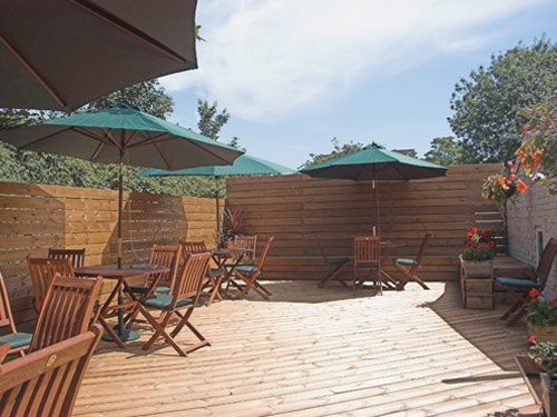 A wooden deck with tables and chairs and umbrellas