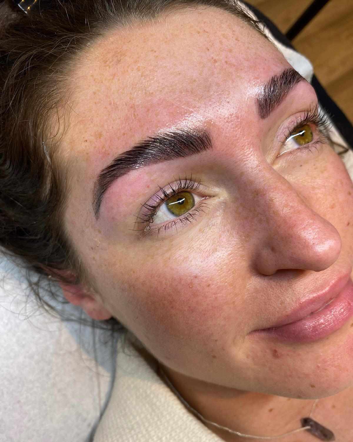 Woman with newly tinted, arched eyebrows; close-up. Skin has redness and shine.