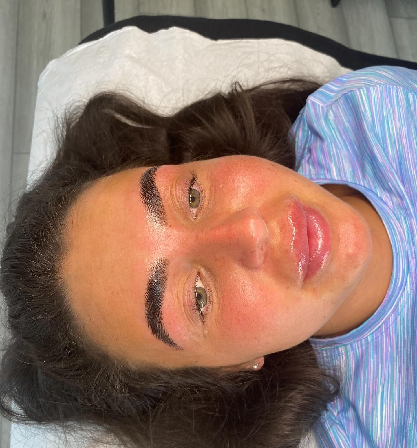 Woman with newly done eyebrows, lying down with glossy skin.