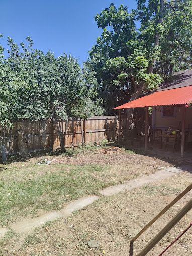 A backyard with a red umbrella and a wooden fence.