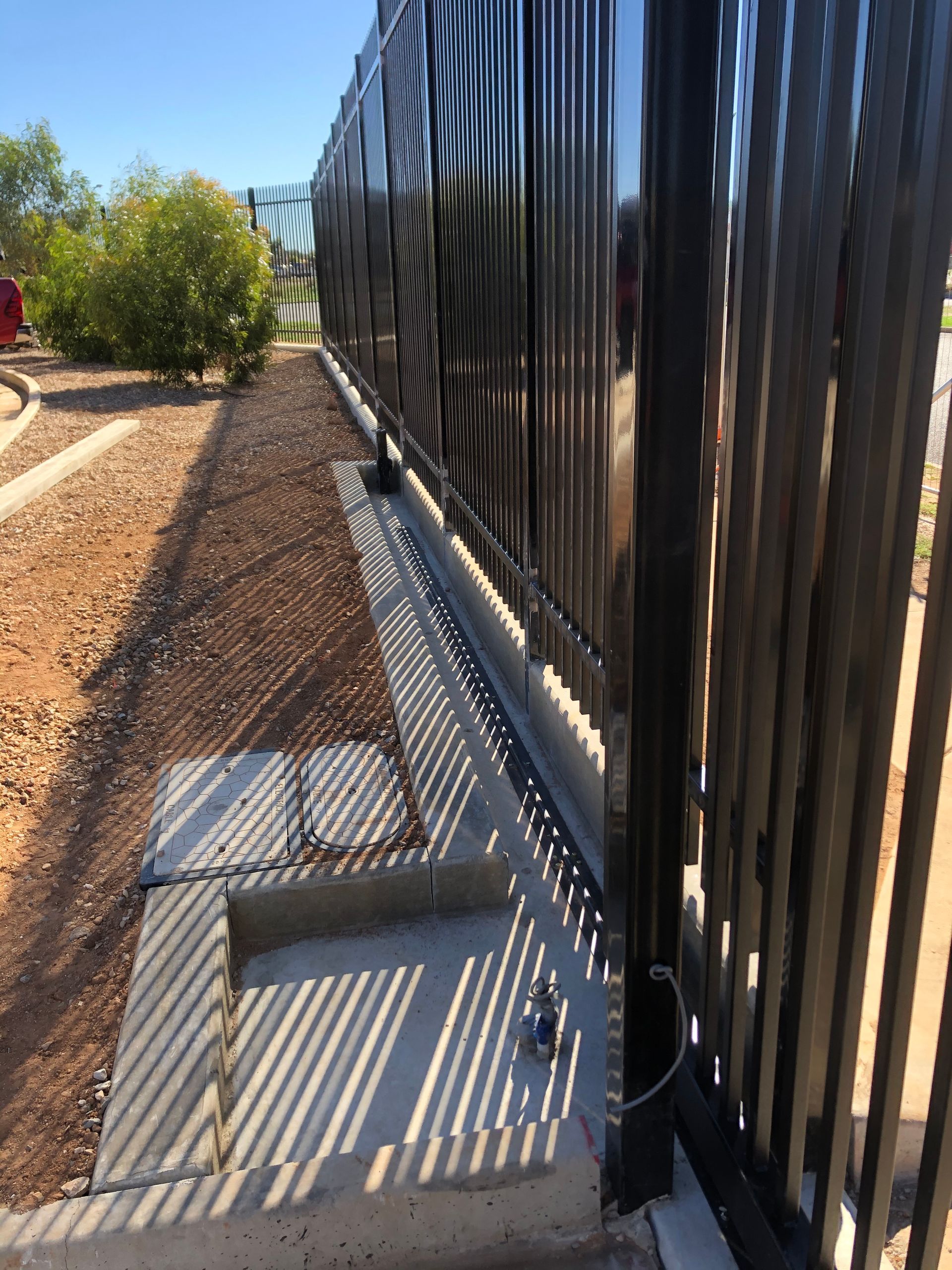 A black metal fence with a shadow on the ground