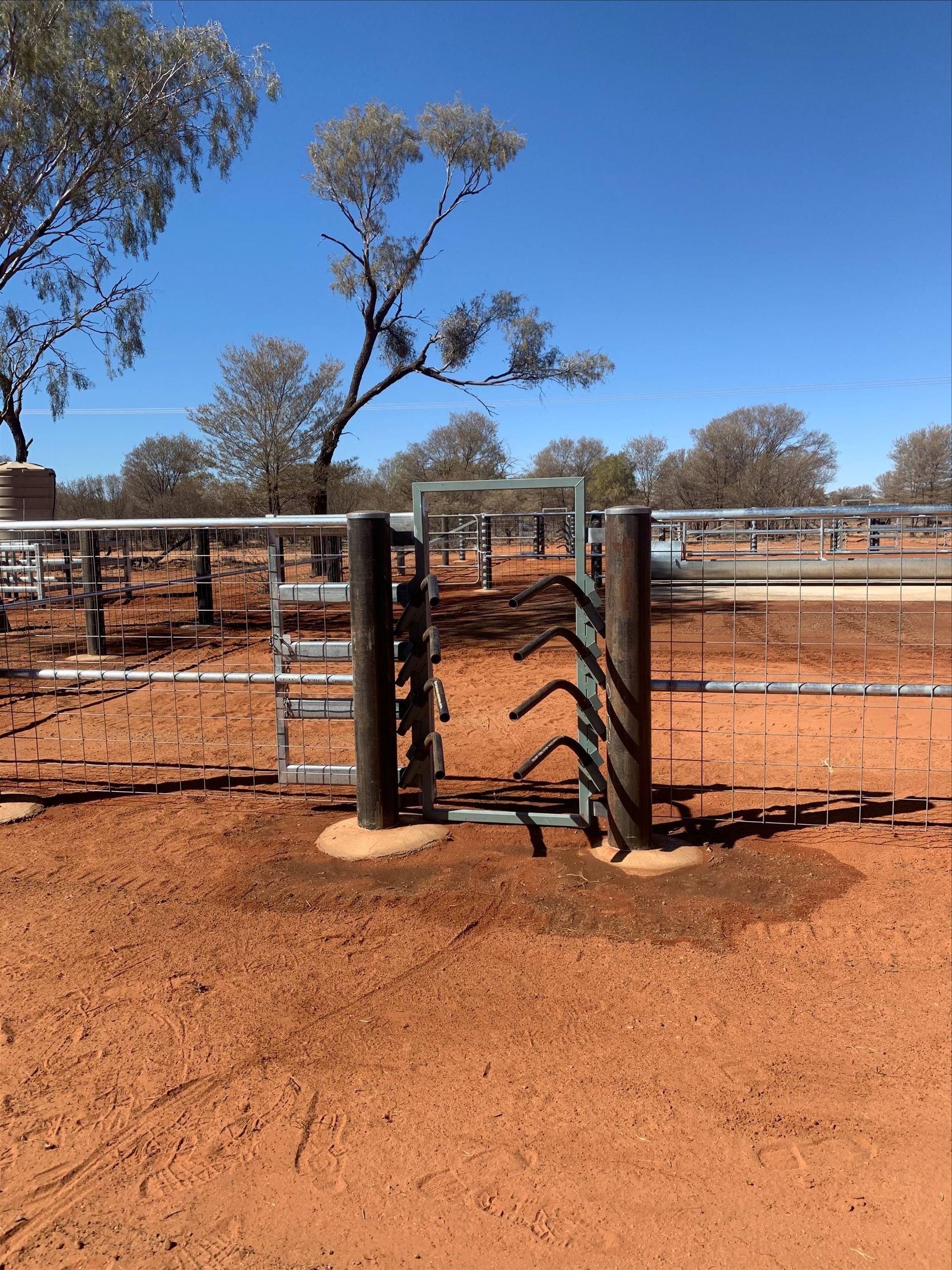 A gate in a dirt field with trees in the background