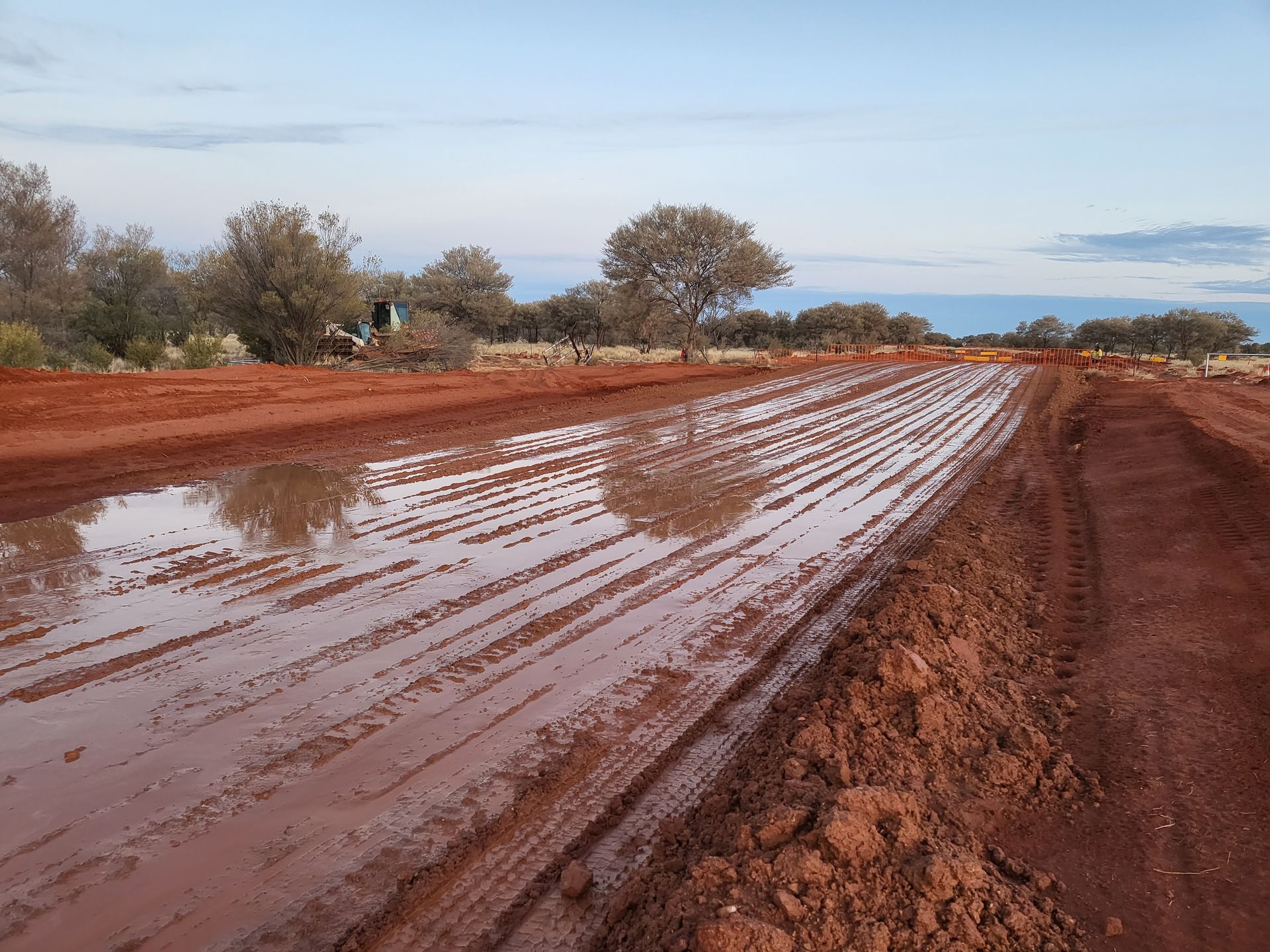 A muddy road with a puddle in the middle of it
