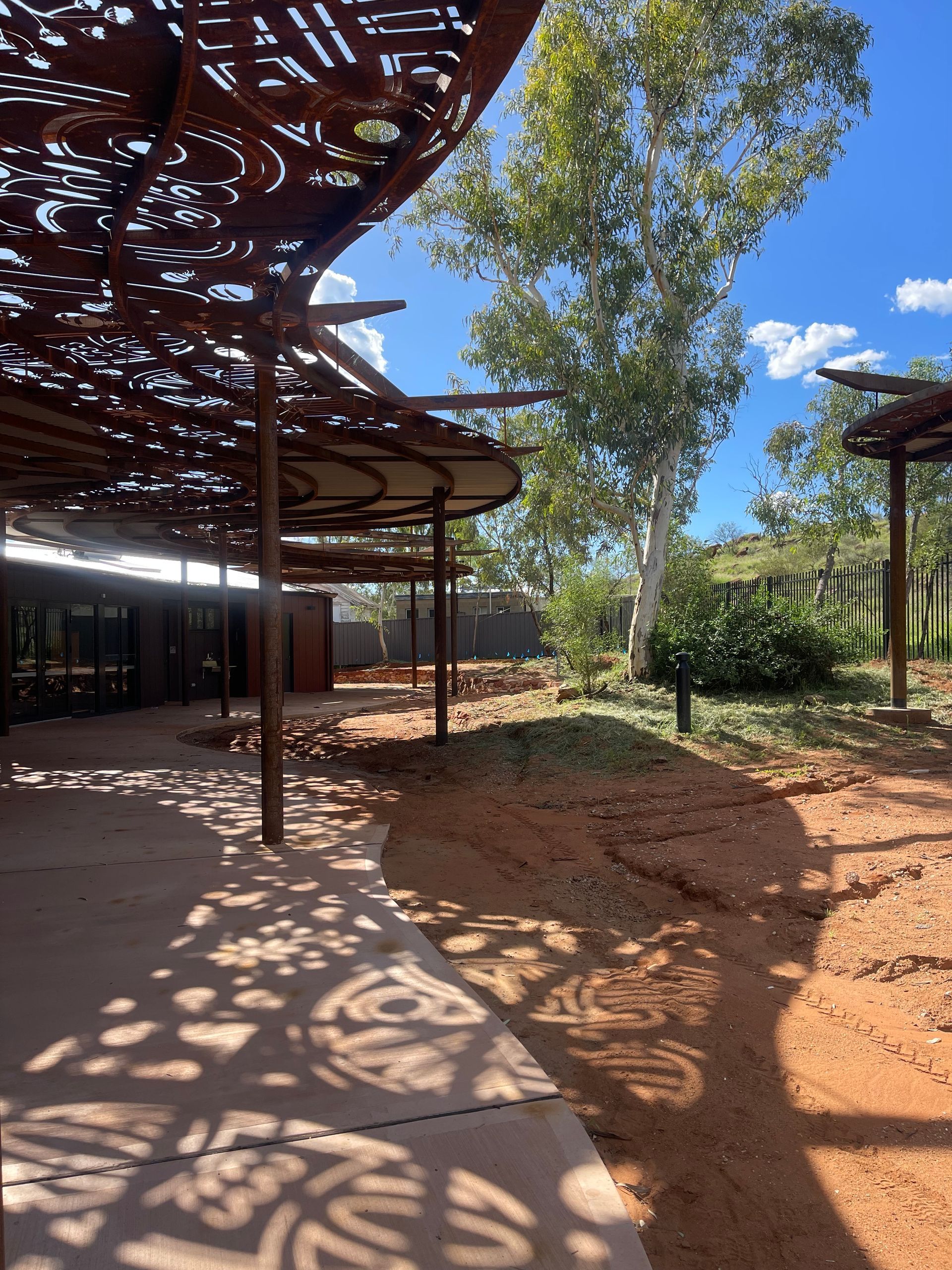 A shadow of a tree is cast on the ground under a canopy