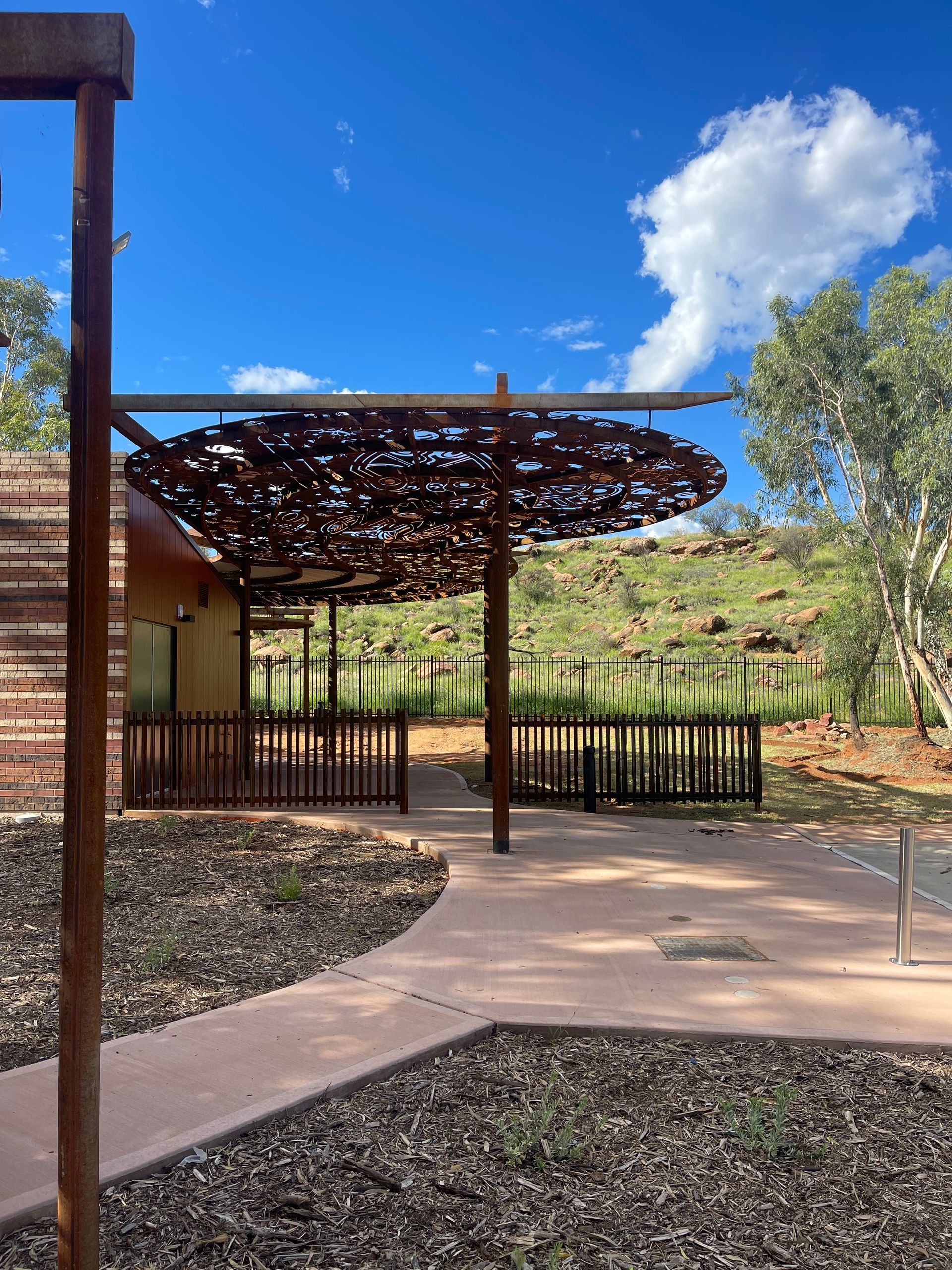 A wooden pergola is sitting in the middle of a lush green field.