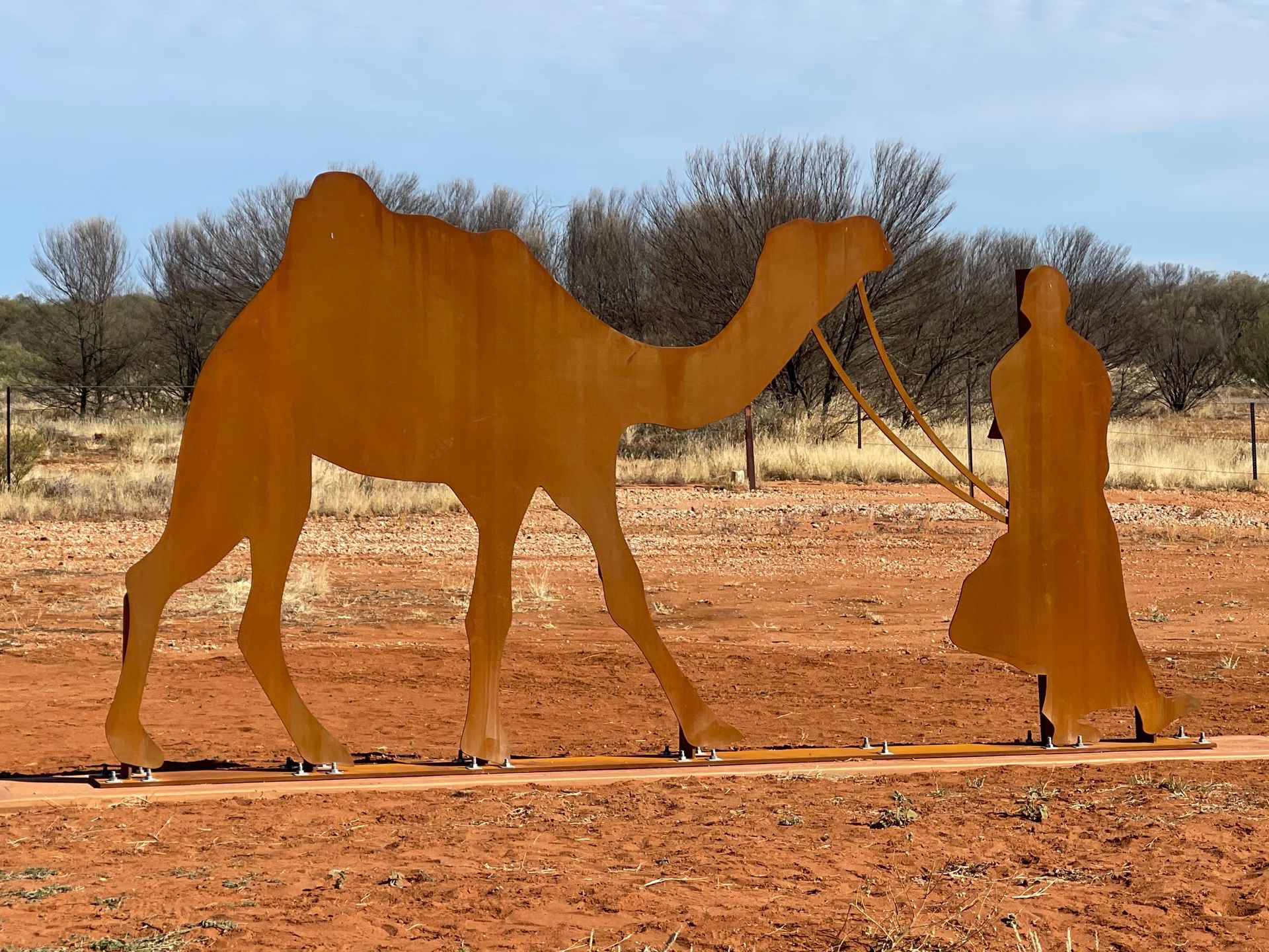 A statue of a man leading a camel in the desert