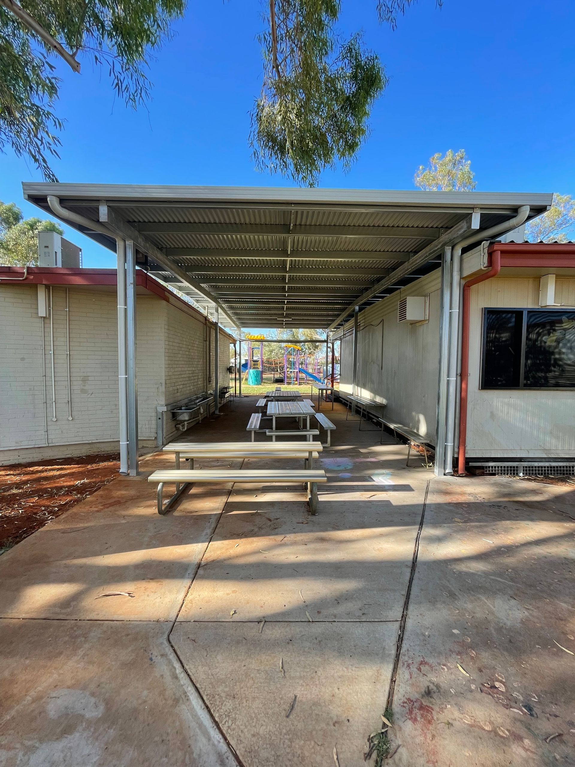 A covered area with tables and benches in front of a building