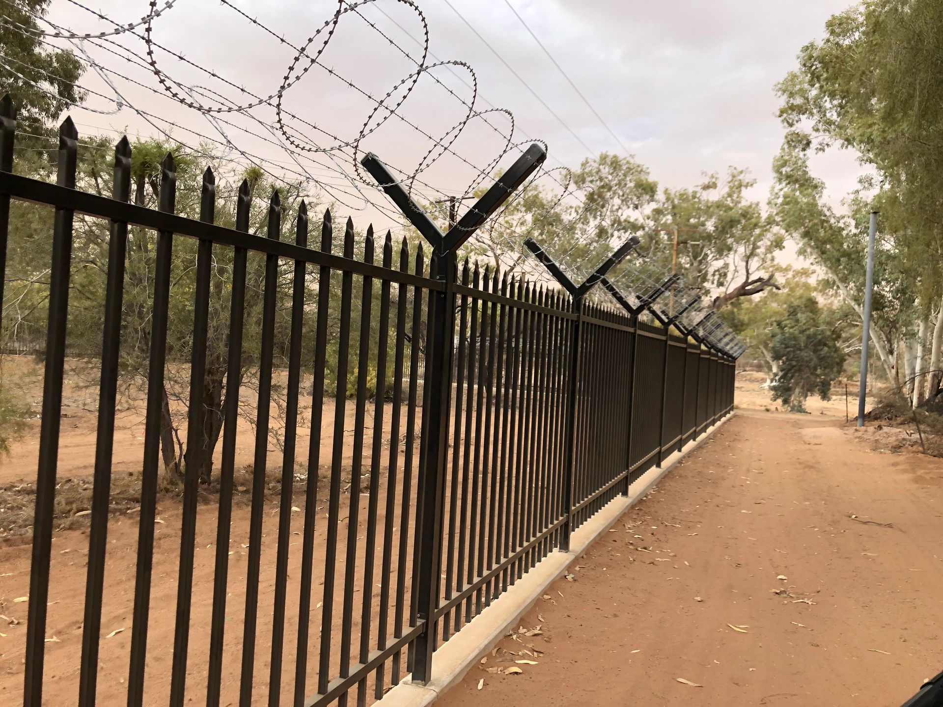 A barbed wire fence along a dirt road