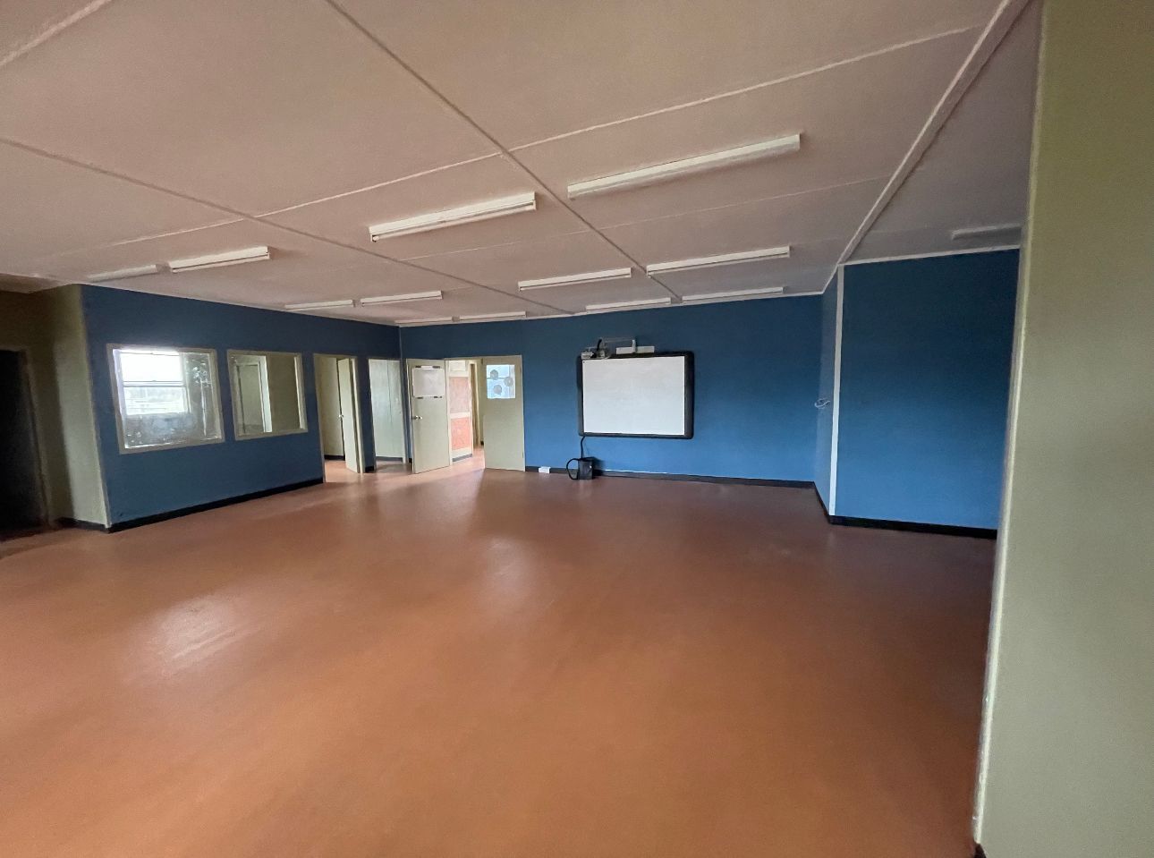 A large empty room with blue walls and a brown floor.