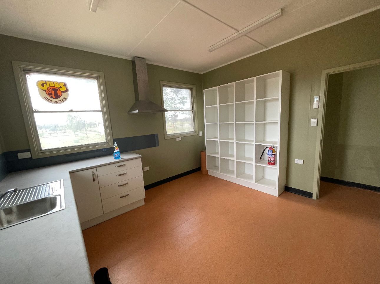 A kitchen with a sink , cabinets , shelves and a window.