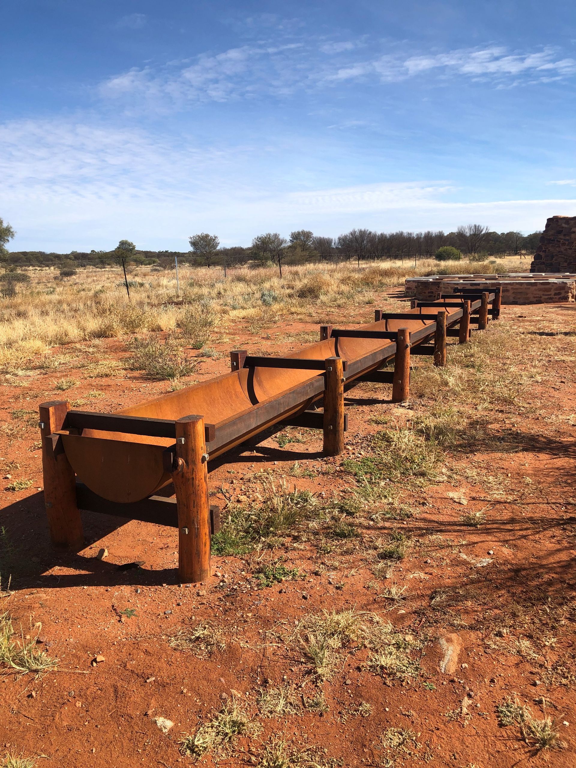 A row of wooden benches sitting on top of a dirt field.