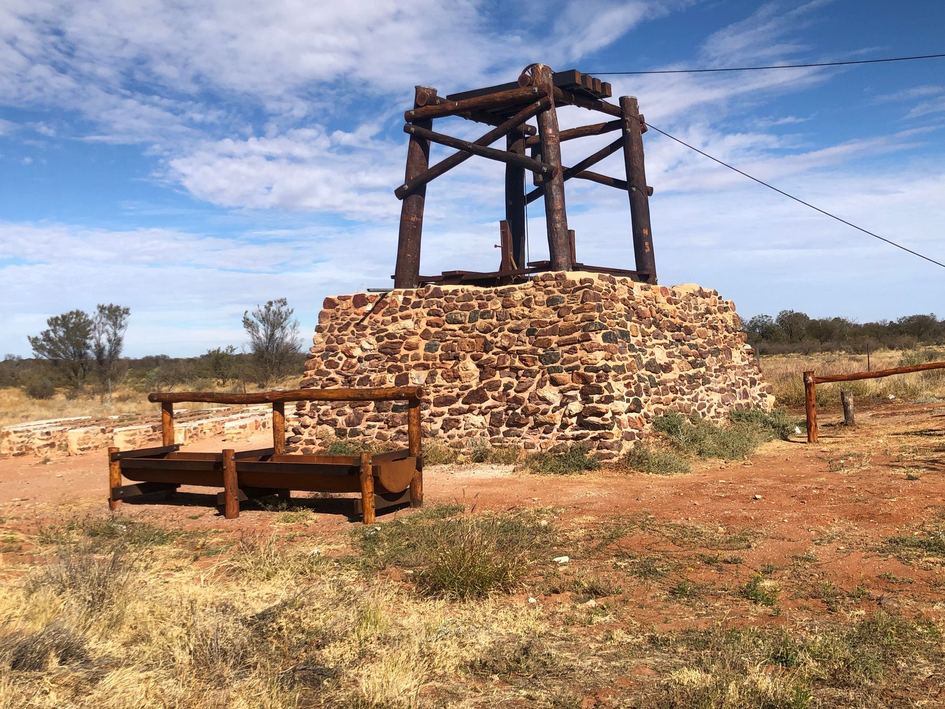 A wooden structure is sitting on top of a pile of rocks in the middle of a field.