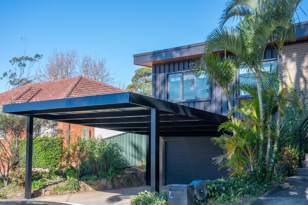 Black Carport Attached to A Two-Story Gray House — Mid North Coast Solar Carports in Coffs Harbour, NSW