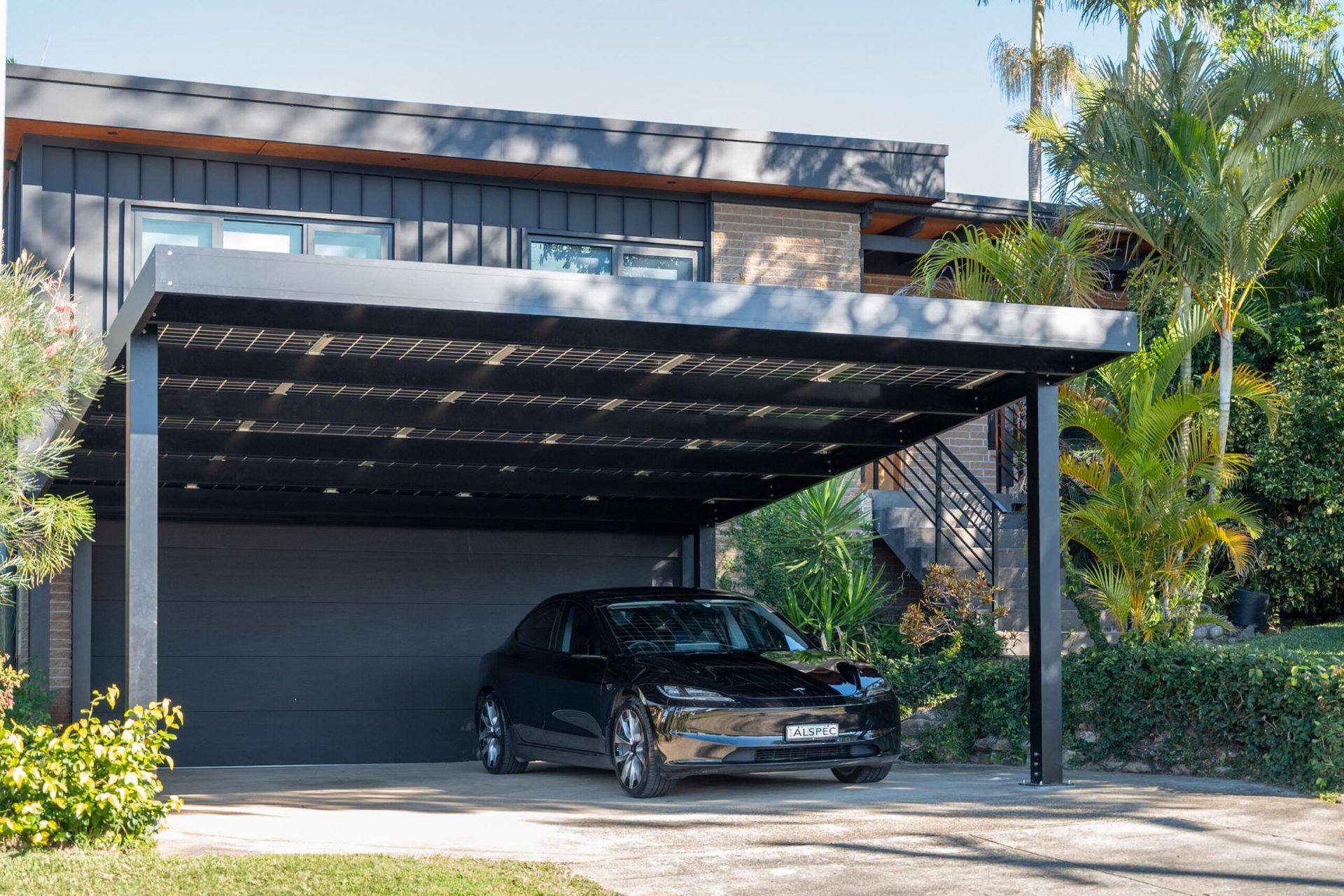 Black Car Parked Under a Black Carport Attached to A House — Mid North Coast Solar Carports in Scotts Head, NSW