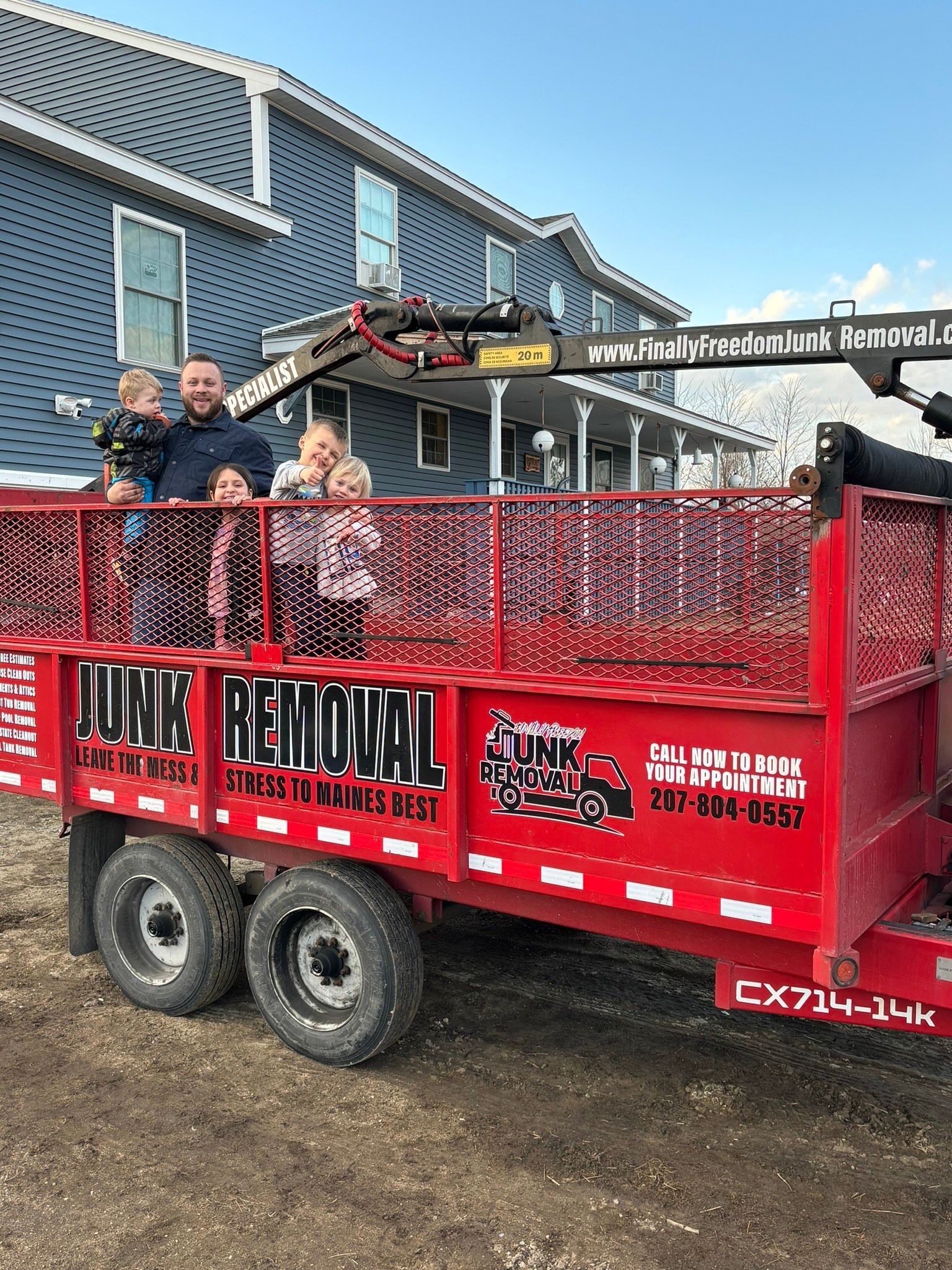 Finally Freedom Junk Removal's family standing in the back of their truck bed