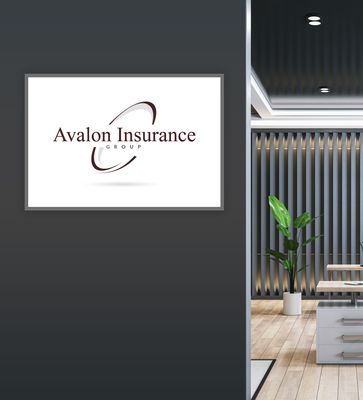 Avalon Insurance Group logo on a wall in an office setting with a plant and desk.