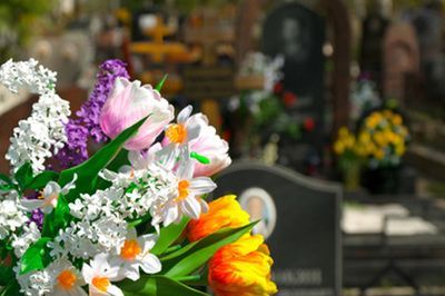 Bouquet of colorful flowers in front of blurred tombstones at a cemetery.