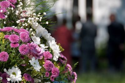 Bouquet of purple and white flowers with blurred people in the background.