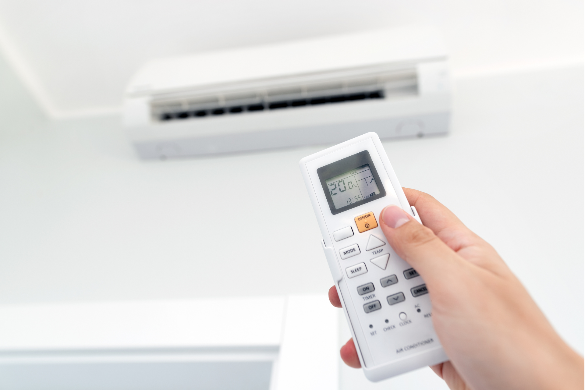 a person is holding a remote control in front of an air conditioner .