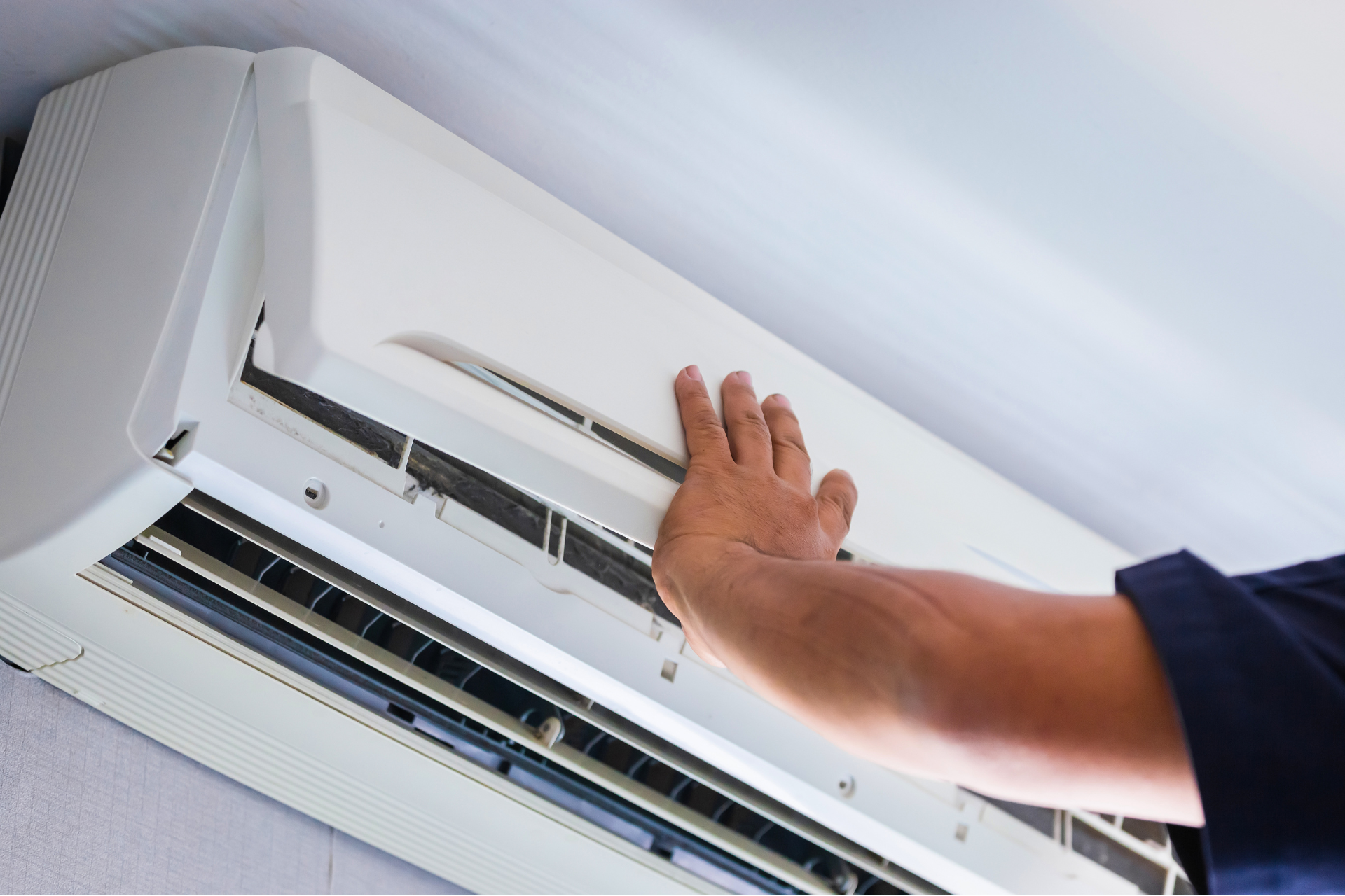 a person is cleaning an air conditioner with their hand .