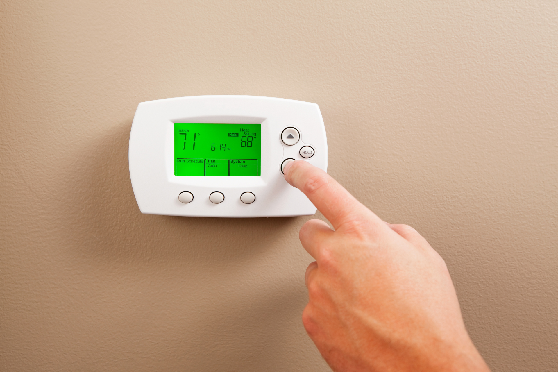 a person is adjusting a thermostat on a wall .