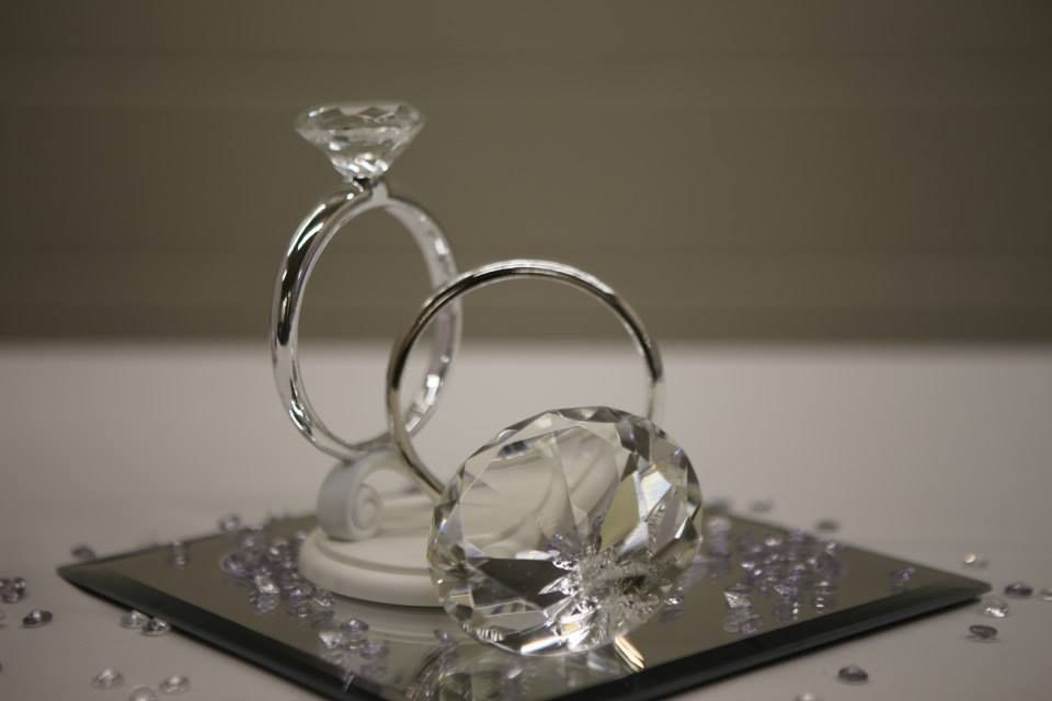 Two decorative diamond rings on a mirror, with small purple gems scattered around.