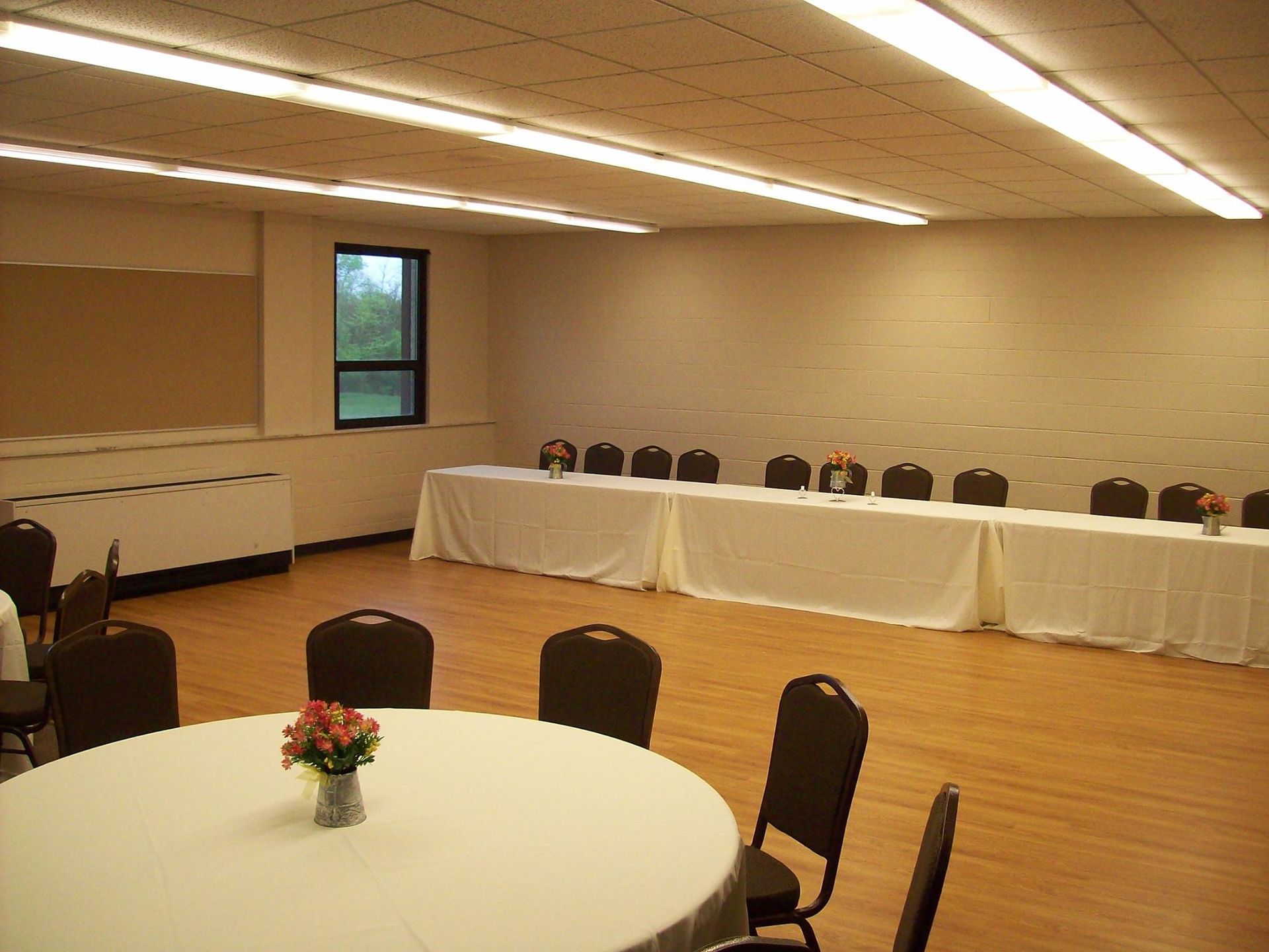 Empty meeting room with round and rectangular tables set for a gathering.